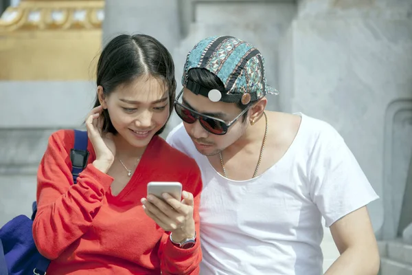 Asya genç erkek ve kadın akıllı telefon isteyen çiftler — Stok fotoğraf