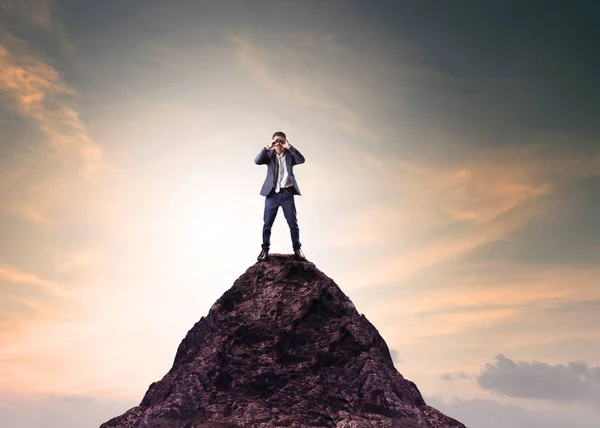 Business man and binocular lens standing on top of mountain — Stock Photo, Image