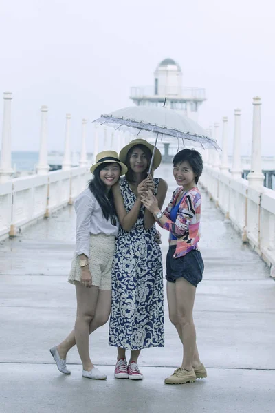 Three of younger asian woman friend under one umbrella in rainy — Stock Photo, Image