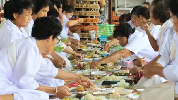 TAILANDIA MAHASARAKHAM - 8 DE JULIO DE 2017: mujer mayor vestida con ropa blanca comiendo comida tradicional en el templo el día del puja asalha del calendario tailandés — Vídeo de stock