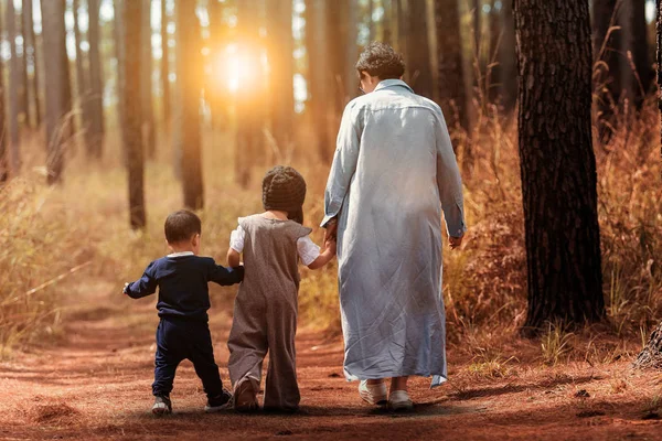 Mutter und zwei Kinder gehen im Kiefernwald spazieren — Stockfoto