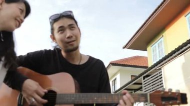 Asya genç erkek ve kadın bahçede oyun gitar rahatlatıcı