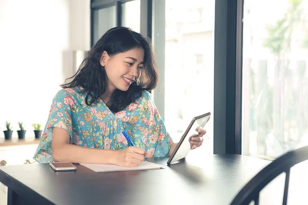 Younger asian freelance woman looking to computer tablet screen — Stock Photo, Image