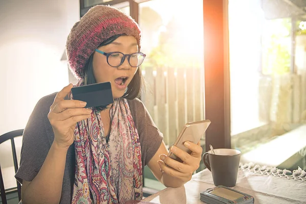 Mulher asiática com cartão de crédito na mão olhando para telefone inteligente e — Fotografia de Stock