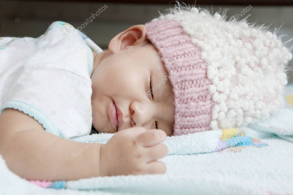 close up face of baby sleeping on clothes bed wearing wool hood 