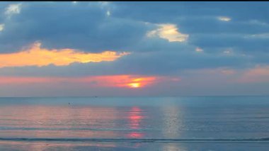 Plajda gün batımına karşı geçen bir araç.