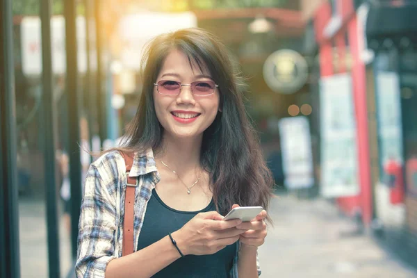 Beautiful aisan woman toothy smiling face with smart phone in ha — Stock Photo, Image