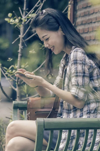 年轻的亚裔女子和智能电话在手里聊天社交媒体哈哈 — 图库照片