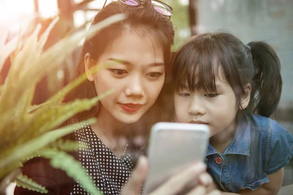 Ásia mais jovem mulher e crianças olhando para inteligente telefone tela um — Fotografia de Stock