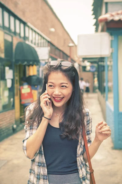 Азиатская молодая женщина покупки и говорить смартфон с улыбкой — стоковое фото