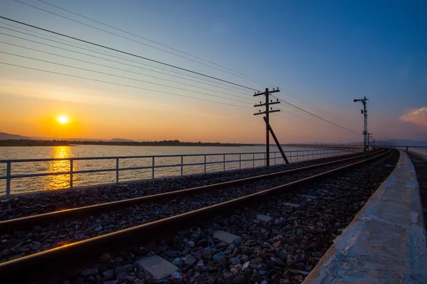 Σιδηροδρομική γραμμή τρόπο πάνω από την δεξαμενή νερού και την όμορφη ανατολή του ήλιου σύνολο ουρανού — Φωτογραφία Αρχείου