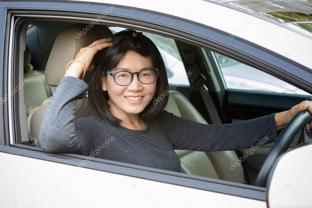 asian woman toothy smiling face driving sedan car 
