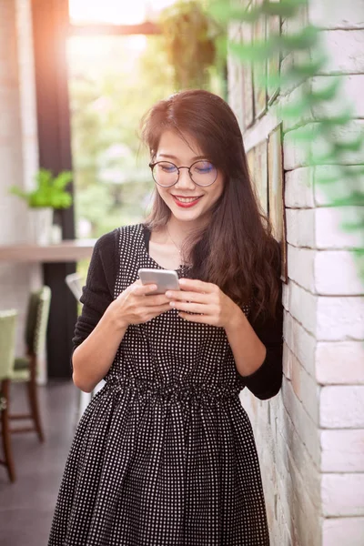 Asiatiska yngre kvinna toothy leende ansikte läsa meddelandet i smart — Stockfoto