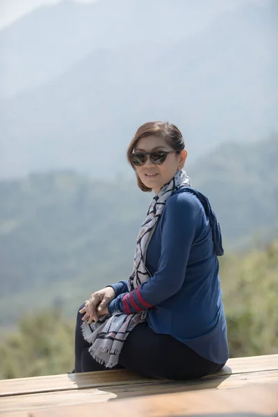 Красивая азиатская женщина сидит на деревянной террасе с зубастой улыбкой — стоковое фото
