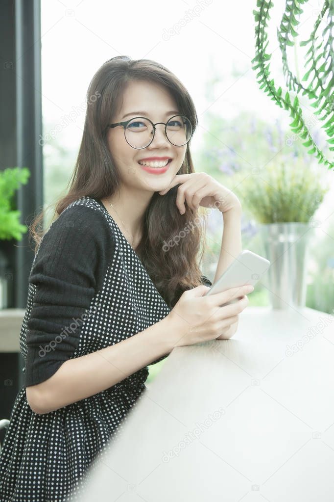 beautiful younger asian woman with smart phone in hand toothy sm