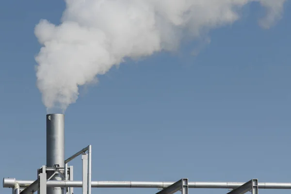 Průmyslové mlha z výfukové trubky proti pozadí modré oblohy — Stock fotografie