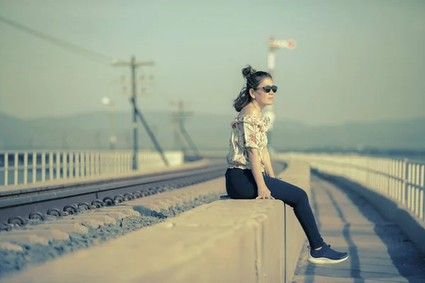 Mujer más joven con gafas de sol sentado al lado de la vía férrea — Foto de Stock