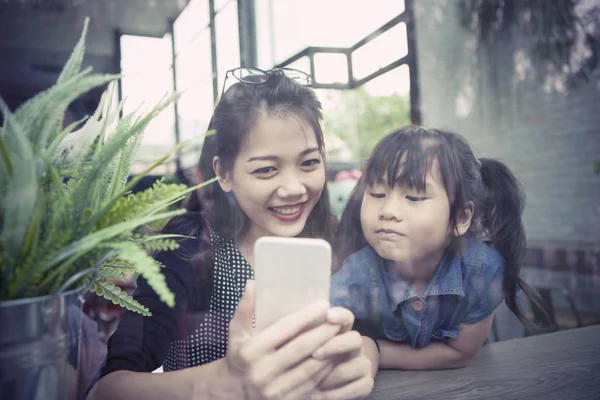 アジアの若い女性と子供たちにスマート フォンの画面を見て、 — ストック写真