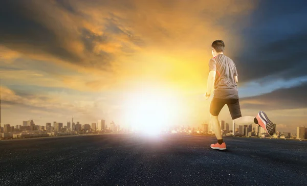 Άνθρωπος του αθλητισμού που τρέχει σε ασφαλτοστρωμένο δρόμο με ηλιοβασίλεμα του ουρανού και αστικών scen — Φωτογραφία Αρχείου