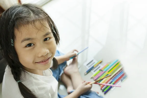 Ansikte av asiatiska barn spelar färg penna på golvet — Stockfoto