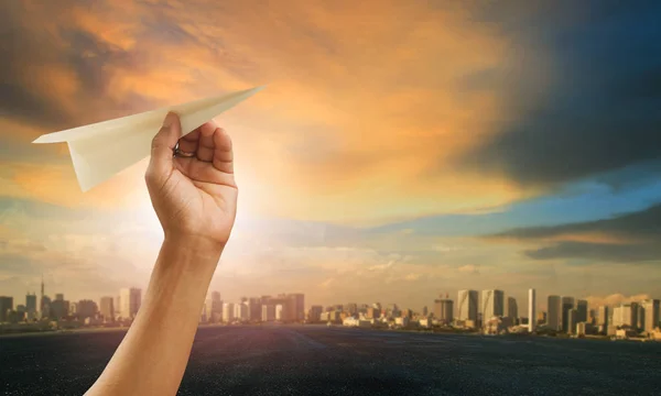 Ручной и бумажный самолет приближается к городскому небу — стоковое фото