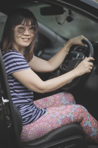 beautiful asian woman sitting on car driver seat toothy smiling