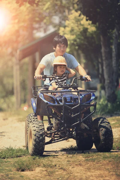 father and daughter riding on quad atv on dirt field