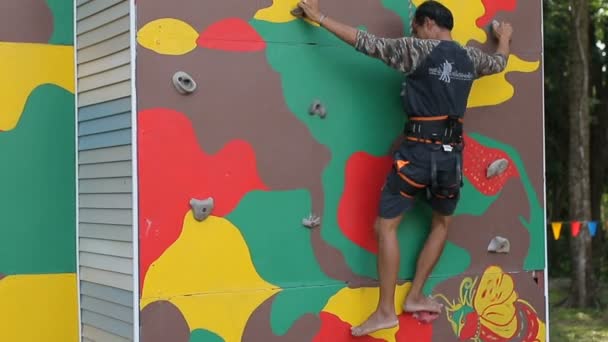 男子身穿安全吊带套装攀登人造石崖 — 图库视频影像