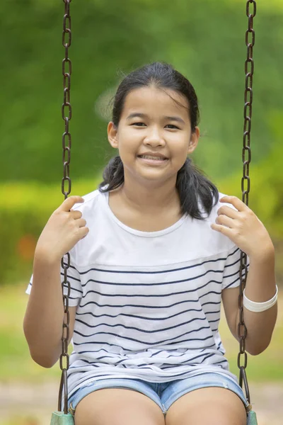亚洲青少年牙齿笑脸坐在绿色公园的秋千上 — 图库照片