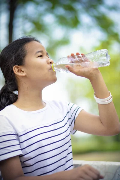 asian teenager drinking water from plastic bottle