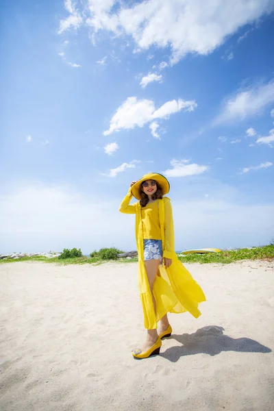 穿着黄色衣服站在海面上的美丽的亚洲女人a — 图库照片