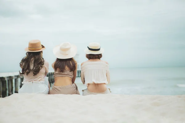Three woman wearing straw hat  sitting on vacation sea beach — Stock Photo, Image