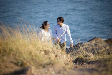 Genç Asyalı erkek ve kadın tatil deniz sahillerinde dinleniyorlar.