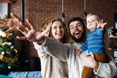 Küçük oğlu olan mutlu ebeveynler oyun oynayıp eğleniyor. Noel havası ve iç mekan. Neşeli duygular ve aile bakışları