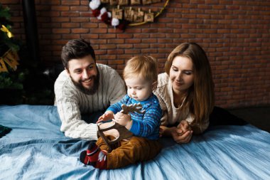Noel arifesindeki dost canlısı aile portresi: genç ebeveynler ve küçük oğul. Noel ailesi bakışı.