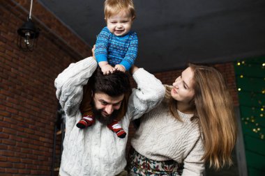 Küçük oğlu olan mutlu ebeveynler oyun oynayıp eğleniyor. Noel havası ve iç mekan.
