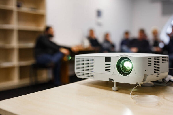 LCD video projector at business conference or lecture in a conference room or office with blurred people background
