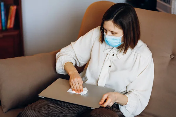 Remote worker disinfects and cleans the working keyboard with antibacterial wet wipes to protect against viruses, germs and bacteria during coronavirus outbreaks and the flu epidemic. Hygiene recommendations, home office concept