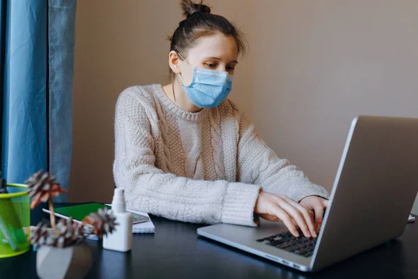 Woman working from home with laptop wearing protective mask. Quarantine, social distancing, stay home, home office concept.Coronavirus pandemic.