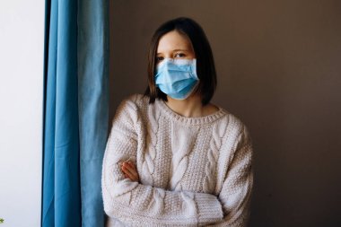Coronavirus salgınları ve grip salgını sırasında virüslerden, mikroplardan ve bakterilerden korunmak için tıbbi maske takan genç bir kadının portresi. Kameraya bak, kapat..
