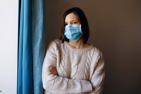 Portrait of young woman wearing a medical face mask, to protect against viruses, germs and bacteria during coronavirus outbreaks and the flu epidemic. Looking at camera, close up.