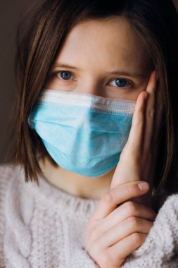 Coronavirus salgınları ve grip salgını sırasında virüslerden, mikroplardan ve bakterilerden korunmak için tıbbi maske takan genç bir kadının portresi. Kameraya bak, kapat..