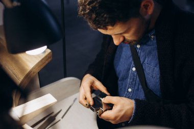 Kuyumcu tezgahındaki bir mücevher parçasıyla çalışıyor. El sanatları insanları sanat konsepti. Gümüş yüzük yapıyor.. 