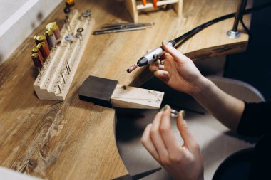 Kadın elleri, gümüş mücevher görünümlü üst görünüm hazırlama işlemini karartıyor. Çalışma araçları masada. El sanatları insanları sanat konsepti. Gümüş yüzük yapıyor..