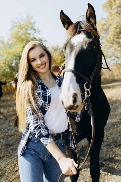 田舎で馬に乗って笑って立っている美しい若い女性の肖像画 — ストック写真