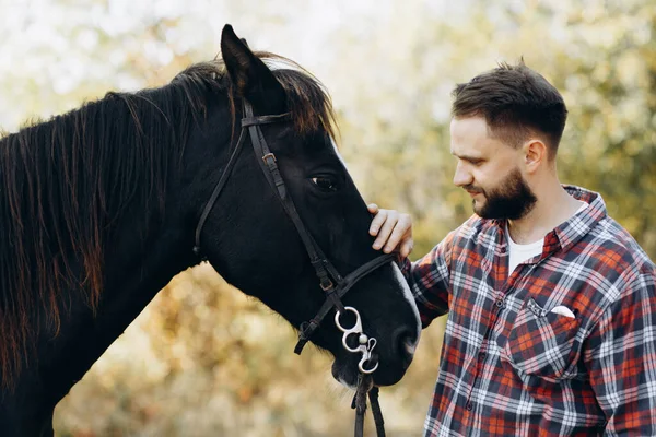 Young farmer cuddling his horse on ranch outdoor. Man loves his  horse. Human and animals relationship concept