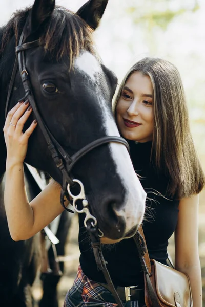 牧場の馬の近くの美しいスタイリッシュなブルネットの女性 笑顔の少女は馬を抱いている 人間と動物の関係の概念 — ストック写真