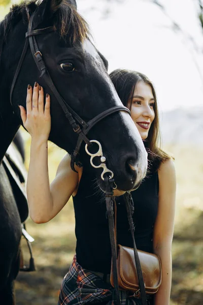牧場の馬の近くの美しいスタイリッシュなブルネットの女性 笑顔の少女は馬を抱いている 人間と動物の関係の概念 — ストック写真