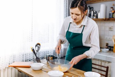 Mutfağında kek için hamur hazırlayan mutlu genç bir kadın. Ev konseptinde aşçılık.