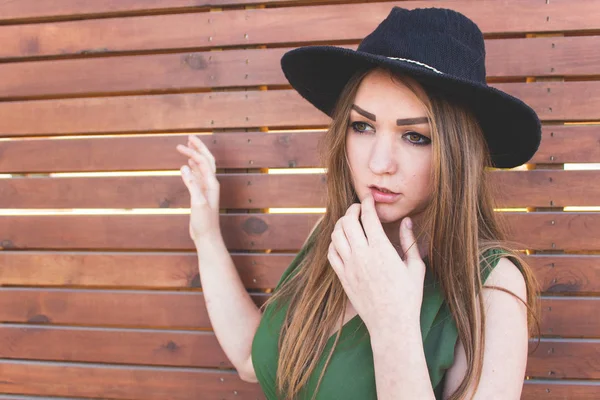 Menina bonita nova em um chapéu preto e vestido longo em um wo marrom — Fotografia de Stock